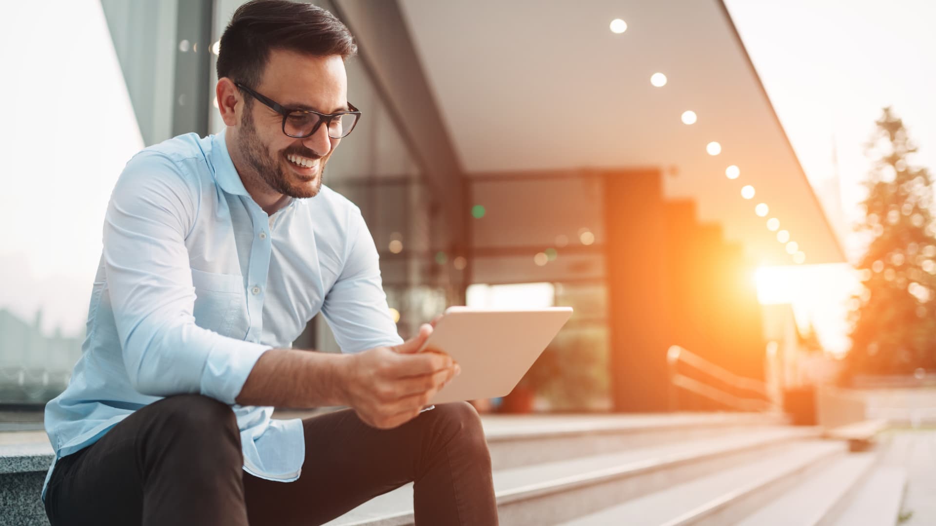 Man die buiten op een betonnen trap zit en een document bekijkt